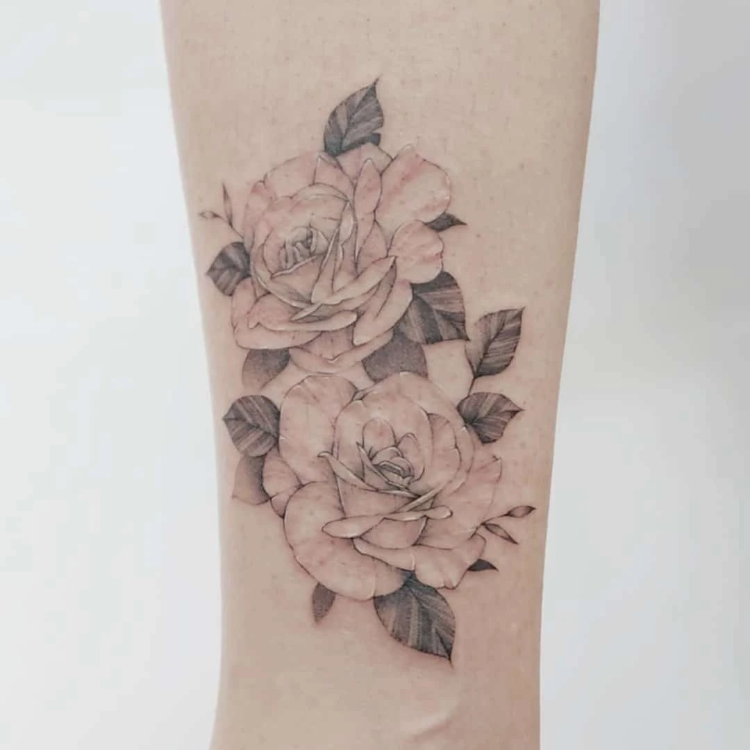 Delicate tattoo of two pink roses on a light skin arm