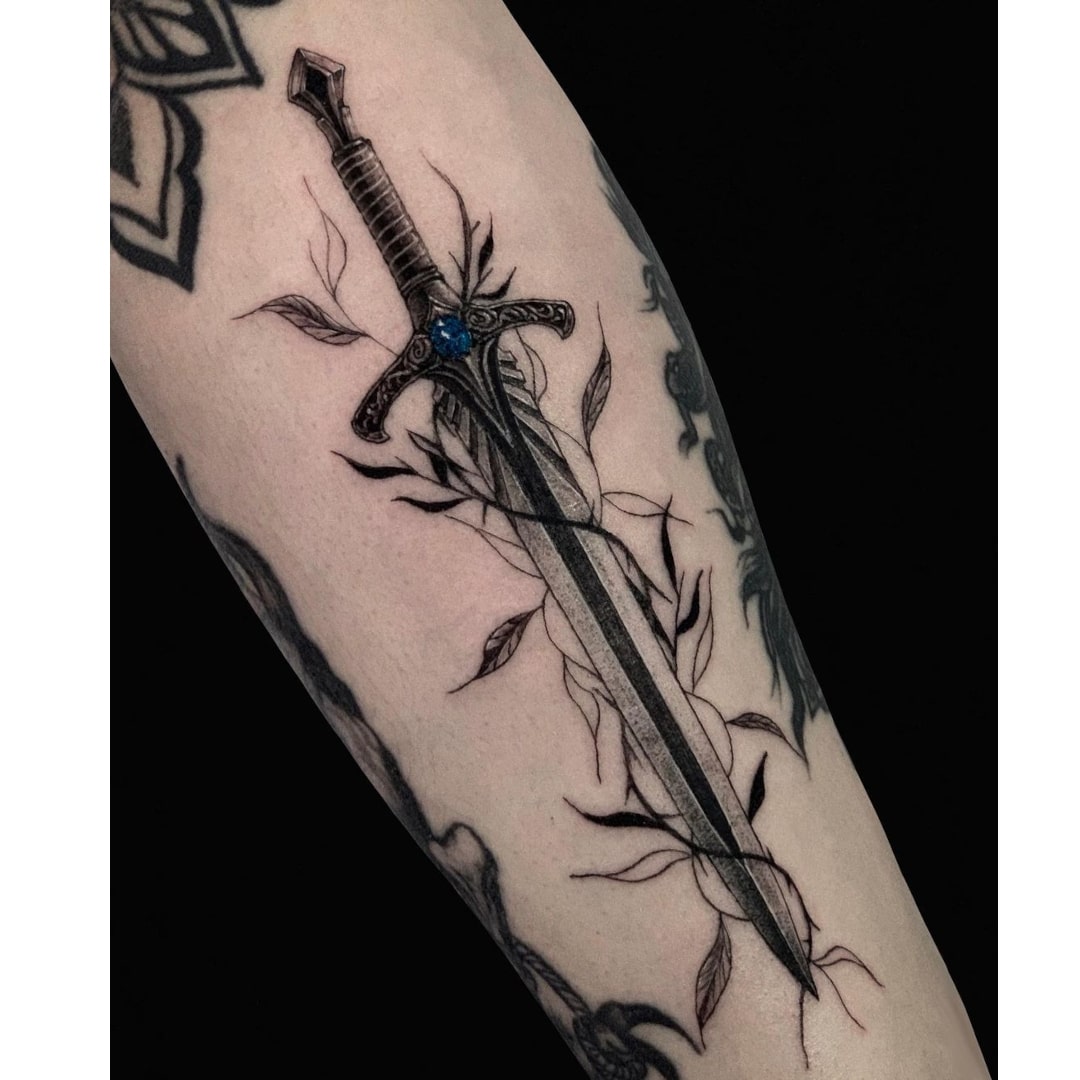 A detailed tattoo of a sword entwined with vines on an arm.