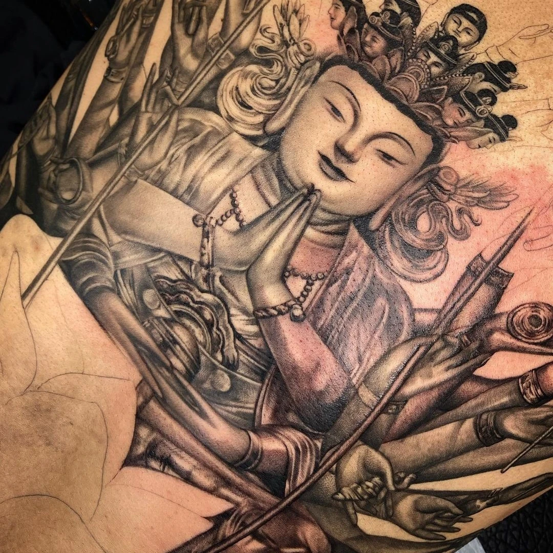 Intricate tattoo art featuring a deity with multiple arms and a serene expression.
