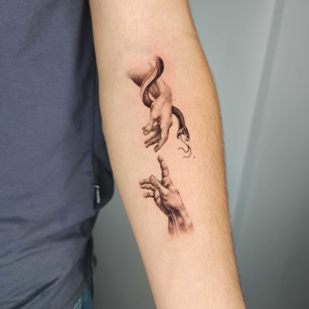 Artistic tattoo of a hand reaching for a snake
