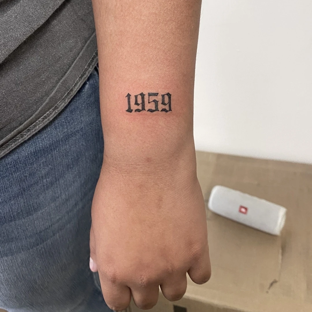 Tattoo of the year '1959' on a person's forearm