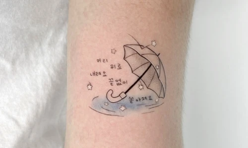 Tattoo design featuring an umbrella and stars on a forearm