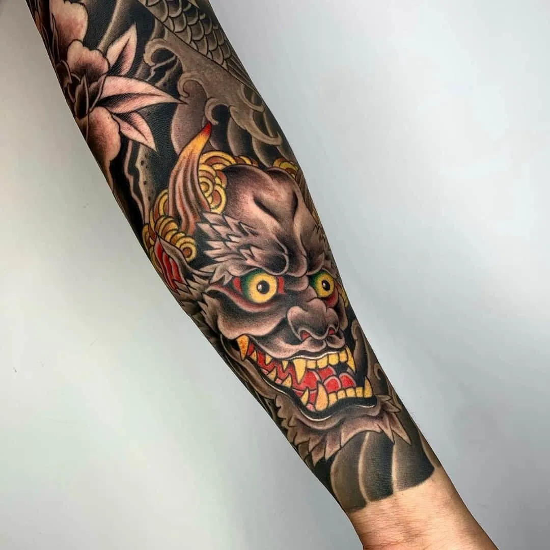Tattoo of a fierce demon face on a forearm.