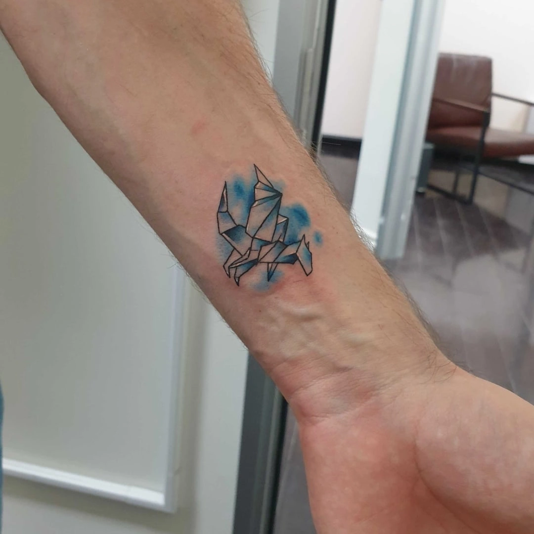 Origami tattoo design on an arm with blue accents