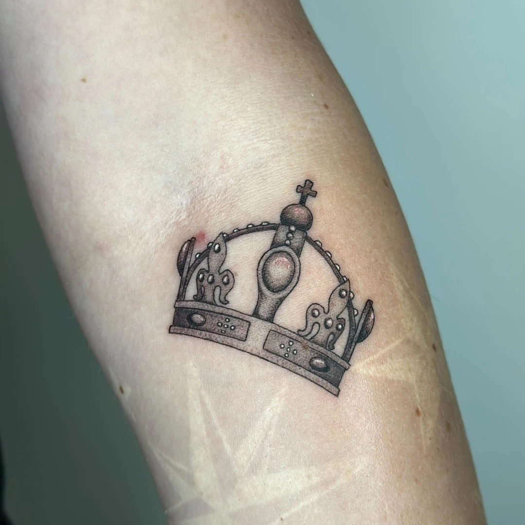 Tattoo of a detailed crown design on a forearm.