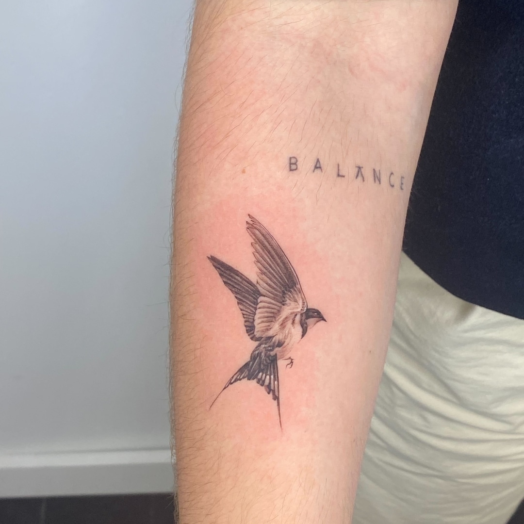 A detailed tattoo of a bird in flight on a person's arm.