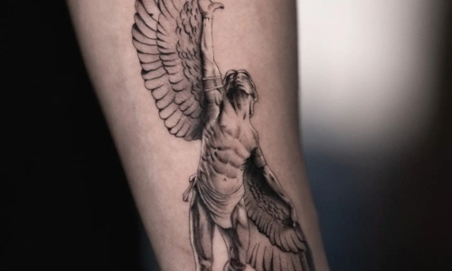Detailed tattoo of a muscular winged figure on forearm