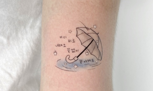 Tattoo of an umbrella on an arm with stars