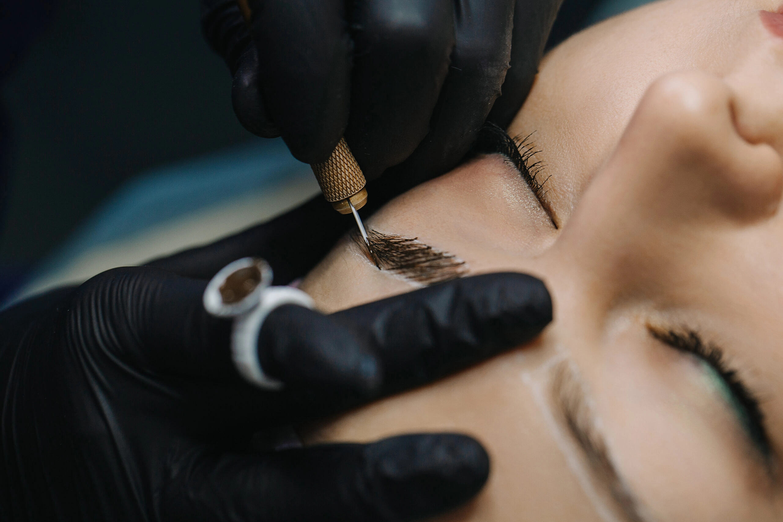 Beauty technician performing microblading on a client's eyebrows