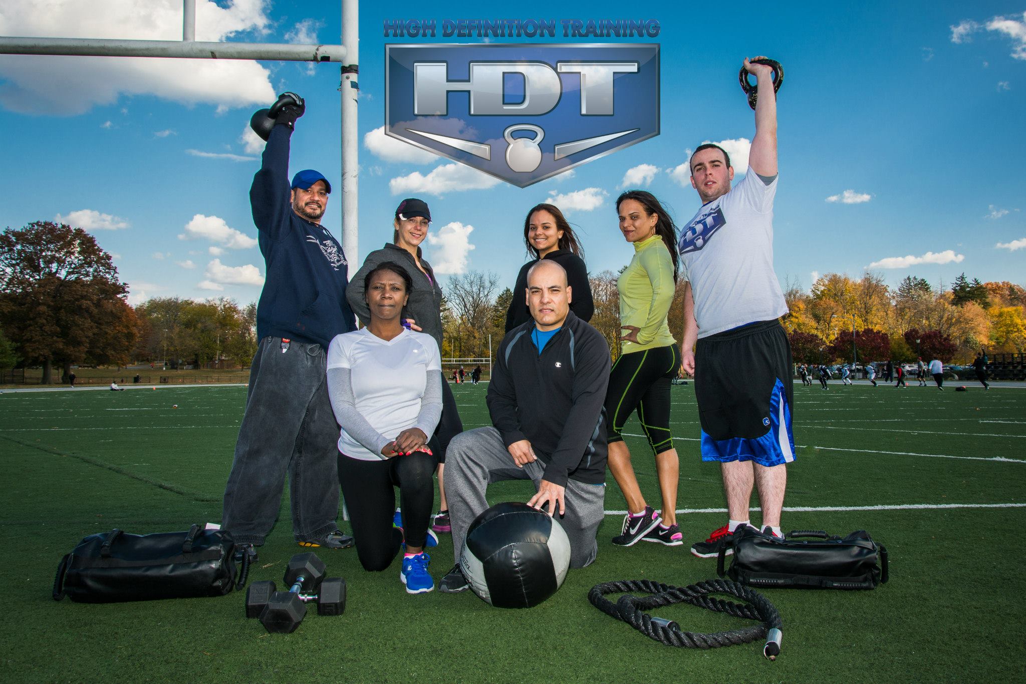 A diverse group of athletes training outdoors in a park with weights.
