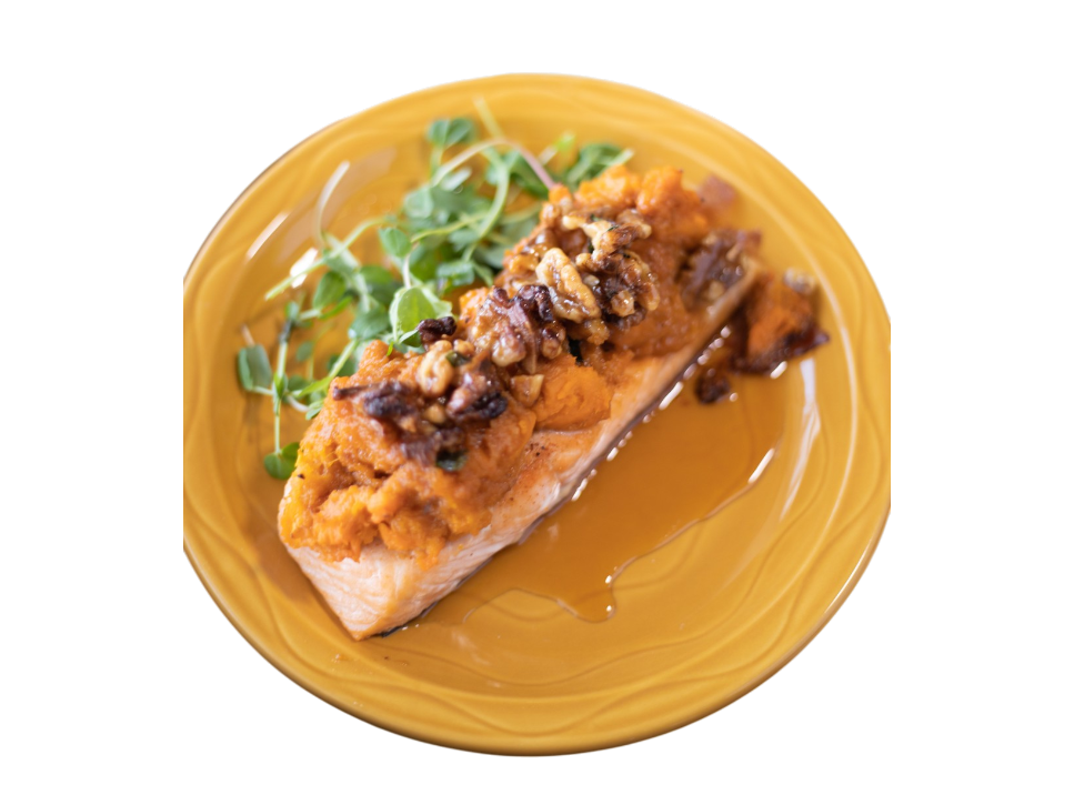 Plated salmon with a nut topping and greens.
