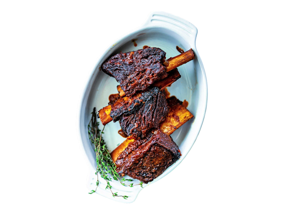 Succulent beef ribs garnished with thyme on a white platter.