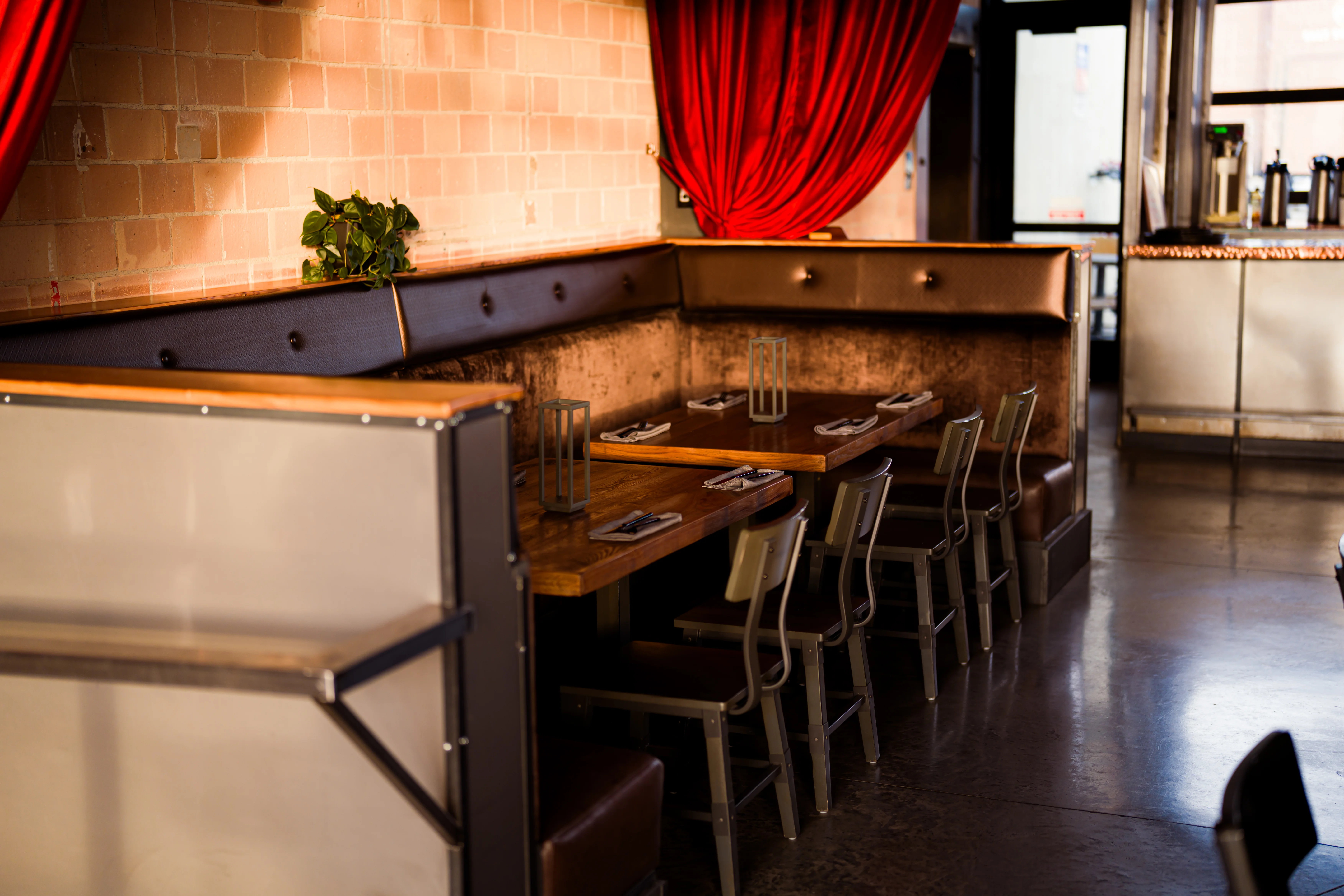 Interior of a cozy restaurant with wooden tables and elegant red drapery.