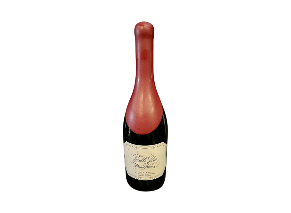 A bottle of sparkling wine with a red foil cap on a black background.