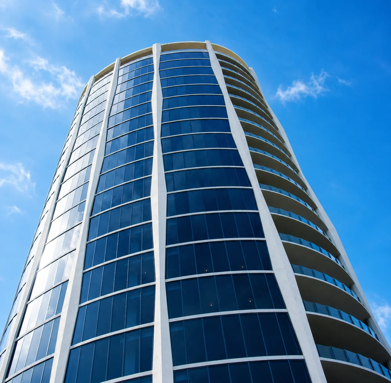 Modern curvilinear skyscraper with glass facade against blue sky