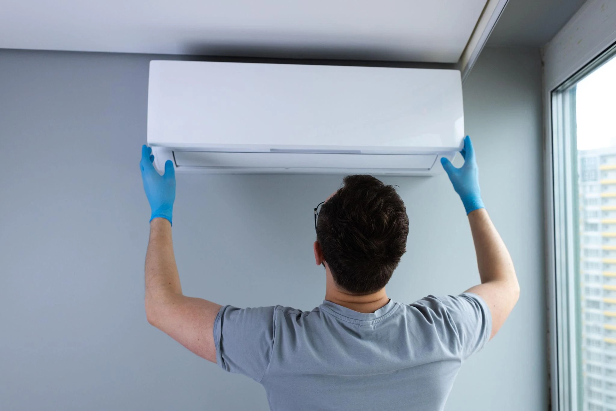 Technician installing air conditioning unit on wall