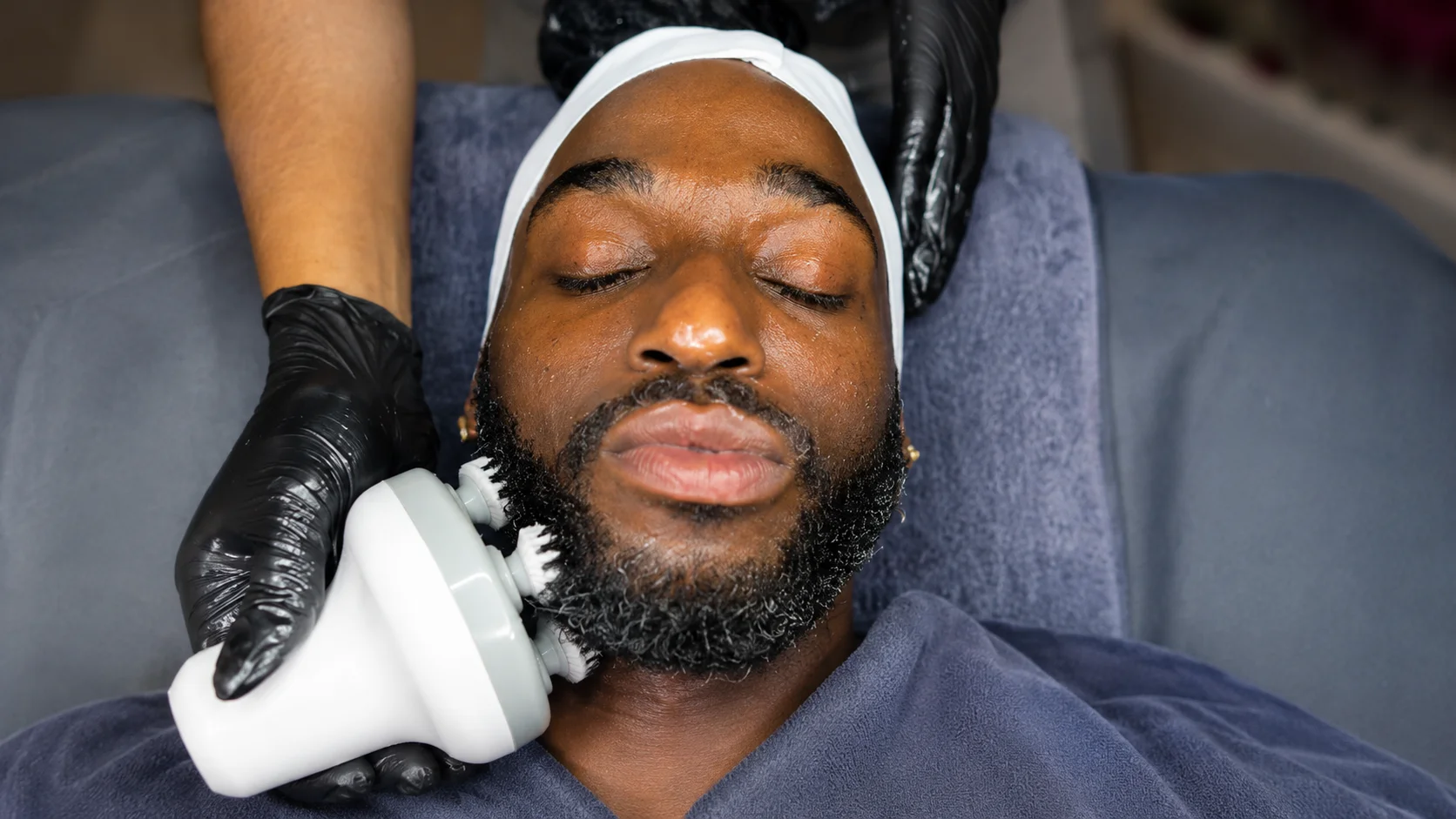 Man receiving facial treatment with a cleansing device