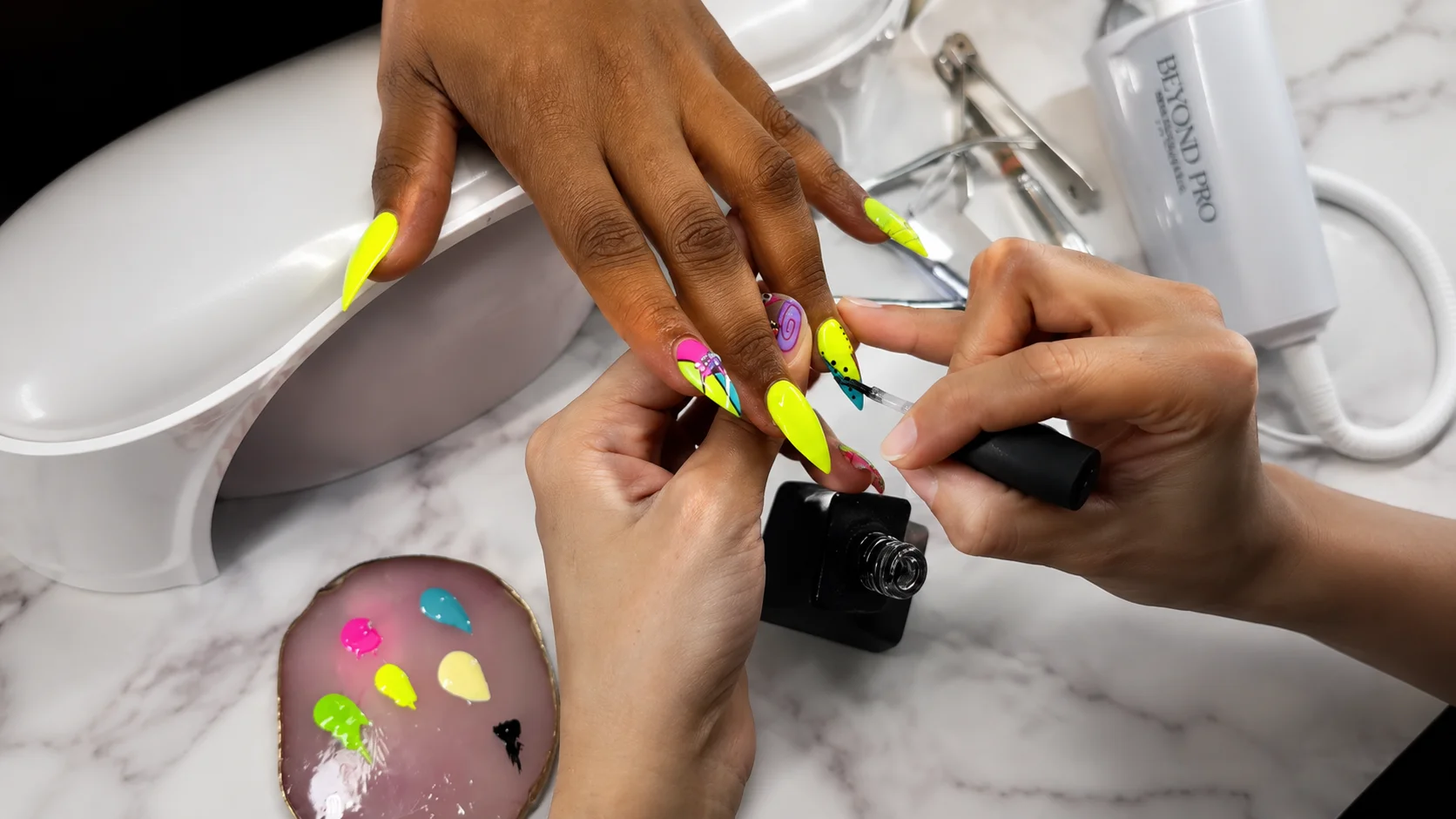 Close-up of hands receiving a colorful nail art treatment