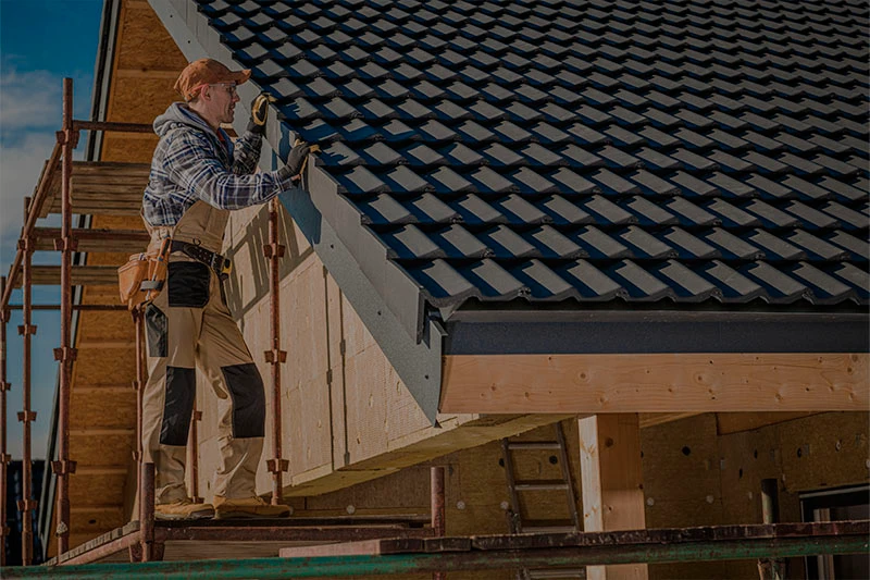 Worker installing roofing tiles on a house