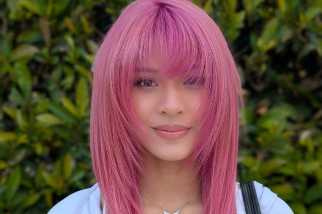 Person with pink hair against green foliage background