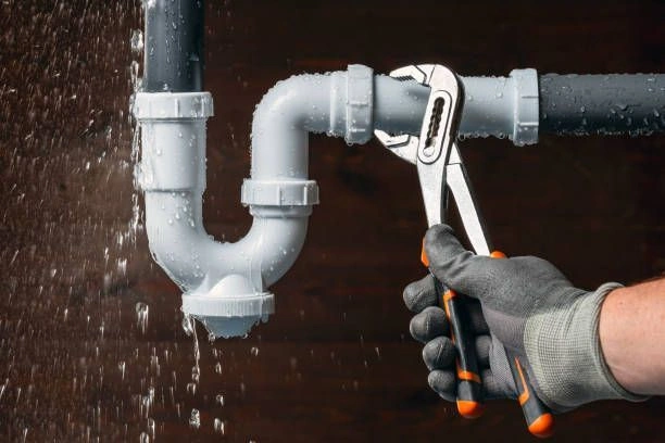 Person using adjustable wrench on leaking pipes