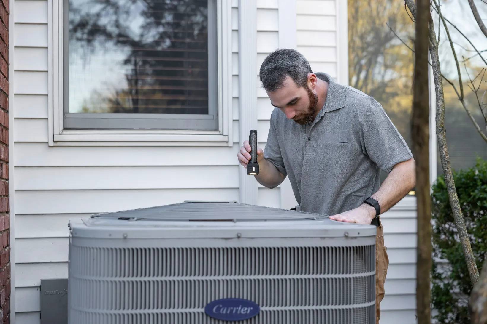 Professional HVAC technician inspecting an air conditioning unit outdoors.