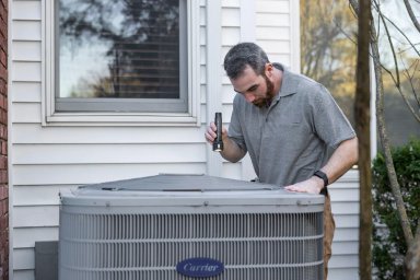 Professional HVAC technician inspecting an air conditioning unit outdoors.