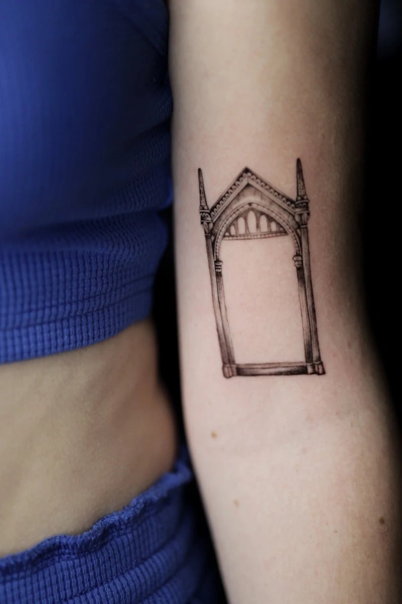 Tattoo of a gothic arch on a woman's arm.