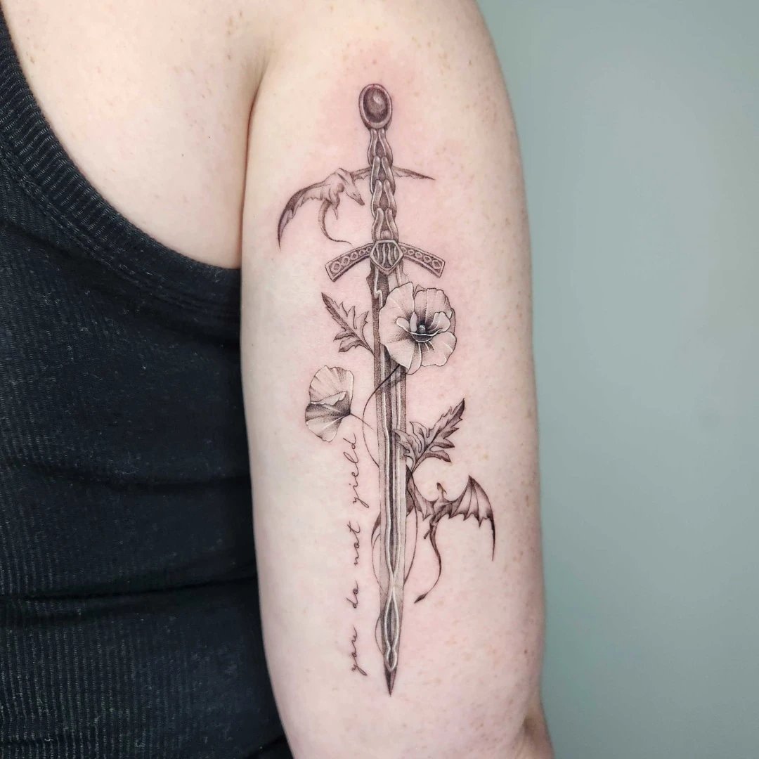 Intricate sword tattoo featuring flowers and bats on arm