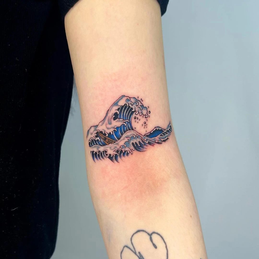 Arm tattoo of a stylized wave in blue and pink tones