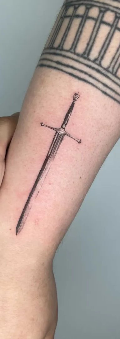 Detailed tattoo of a sword on a person's forearm