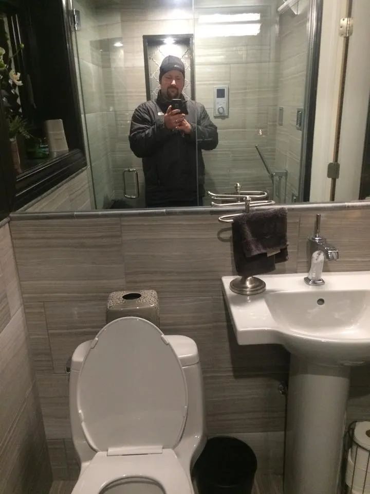 Man taking a selfie in a modern bathroom.