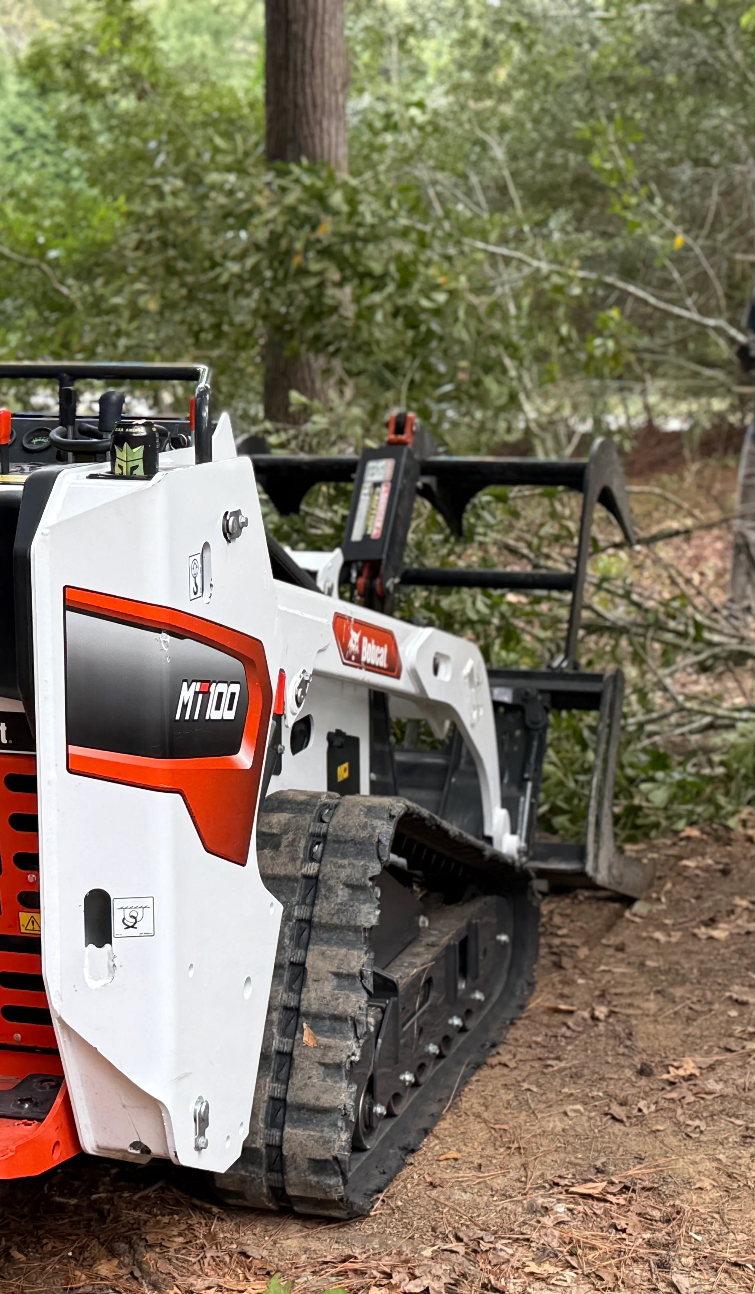 Bobcat excavator clearing branches in the woods