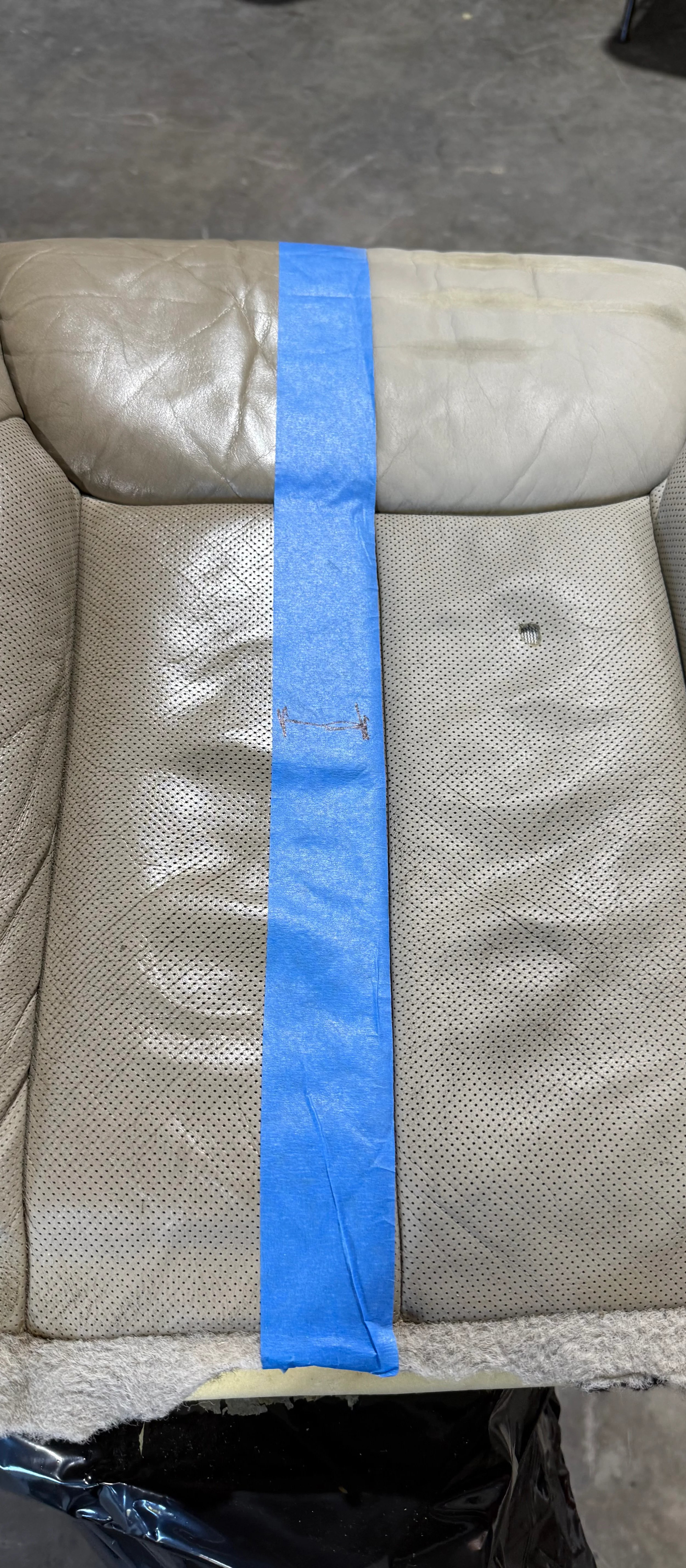 Gray leather seat cushion with blue tape