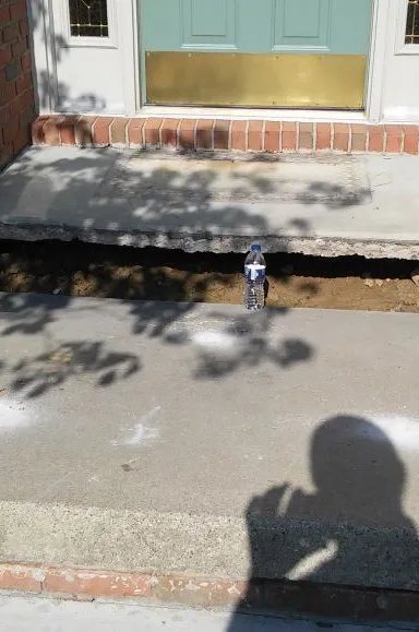 Concrete steps with a hole showing underlying soil