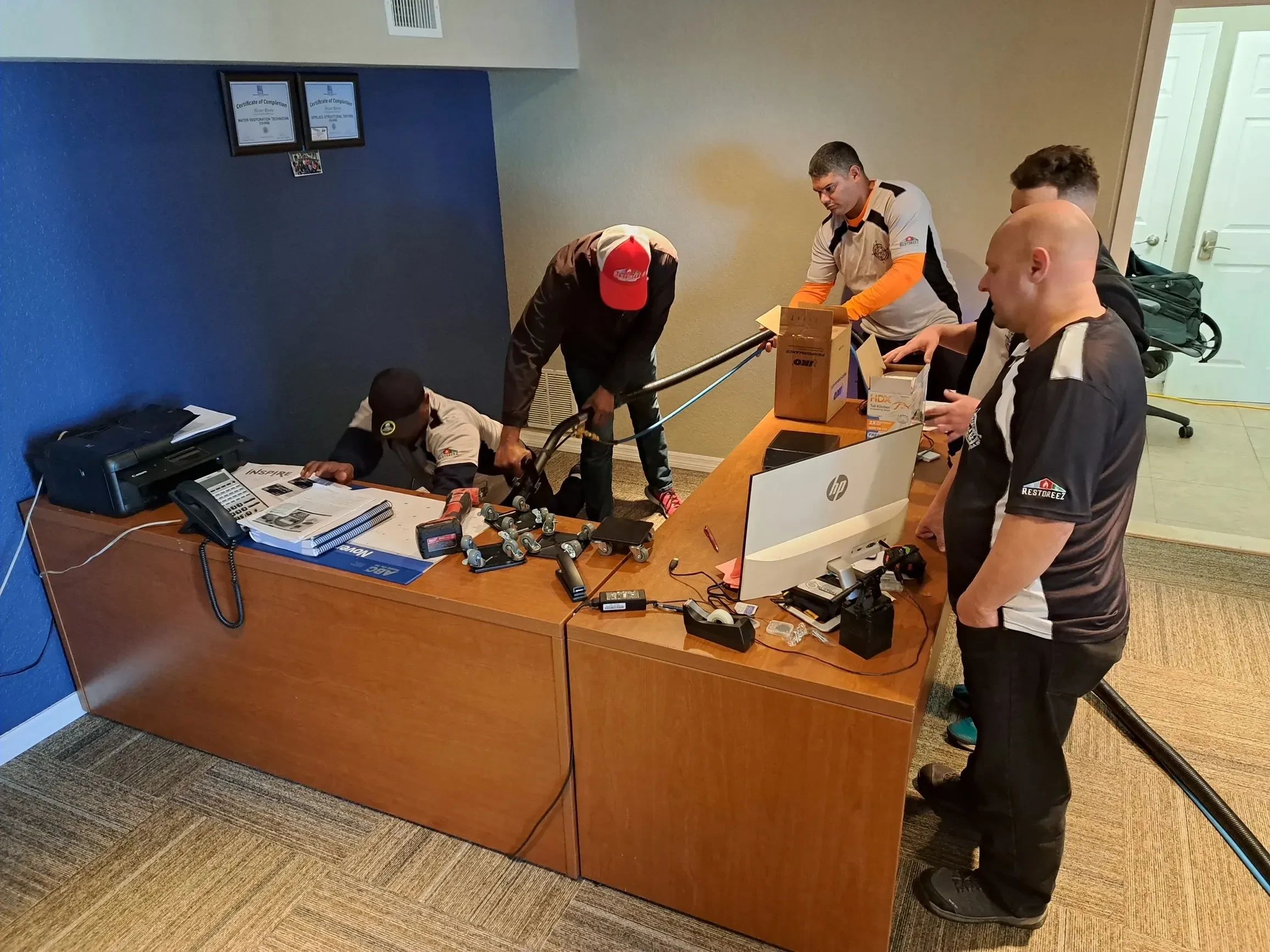 Five people working together at a desk in an office.