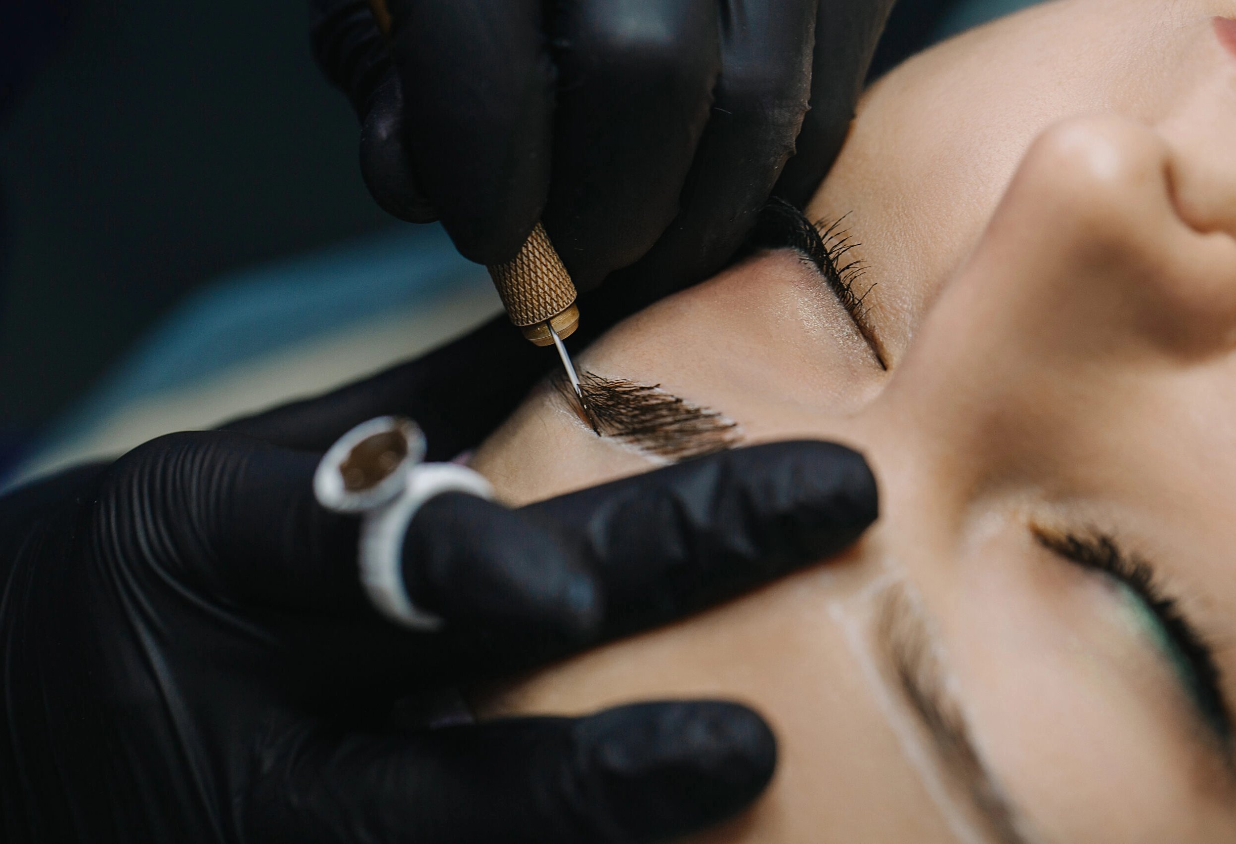 Beauty technician performing microblading on a client's eyebrows