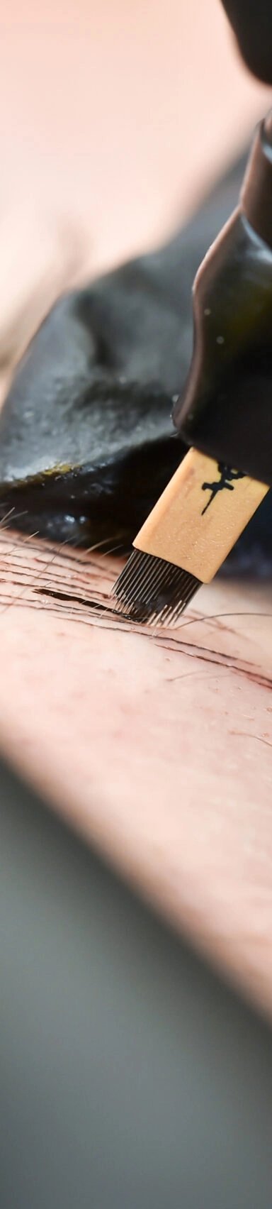 Close-up of eyebrow microblading procedure with a pen.