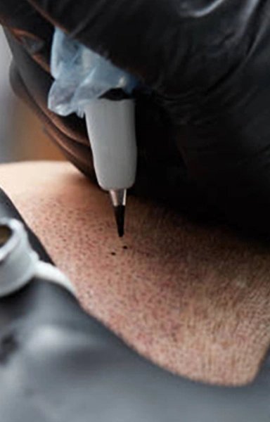 Tattoo artist using a tattoo machine on scalp
