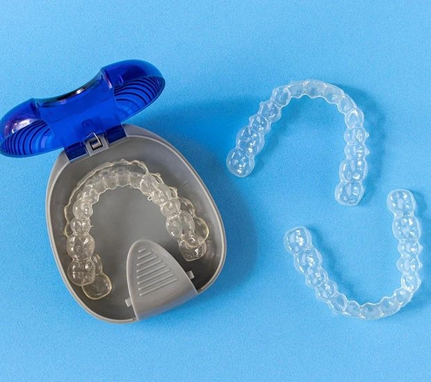 Clear dental aligners in a case on blue background