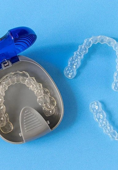 Clear dental aligners in a case on blue background