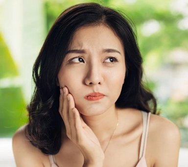 Concerned woman touching her cheek in a well-lit setting