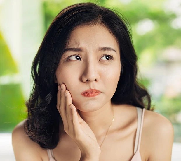 Concerned woman touching her cheek in a well-lit setting