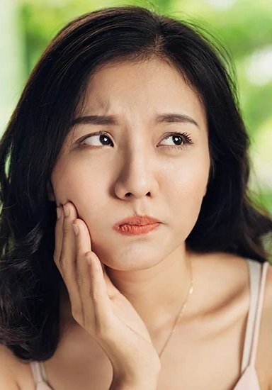 Concerned woman touching her cheek in a well-lit setting