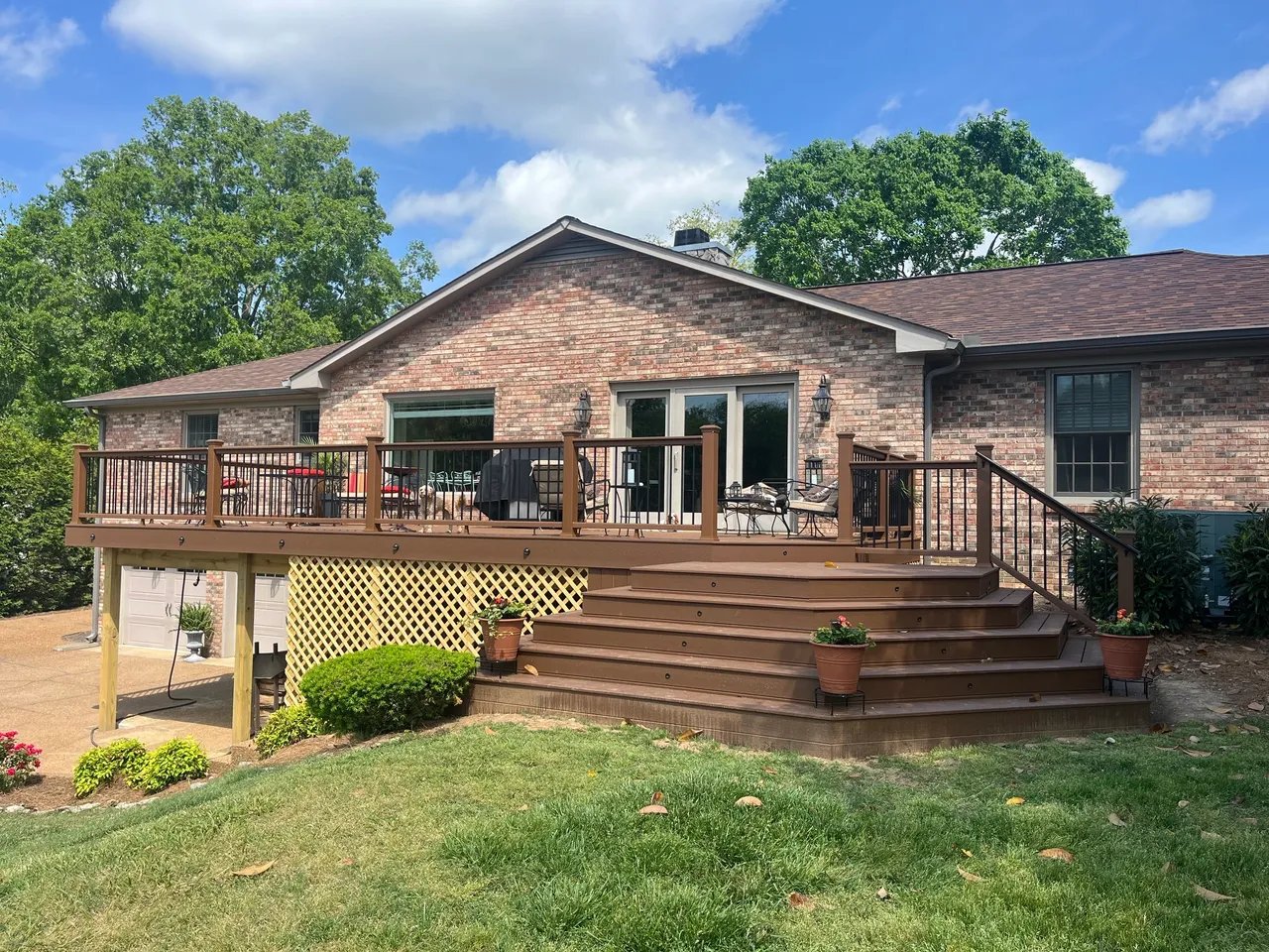 Exterior view of a brick house with a wooden deck and garden.