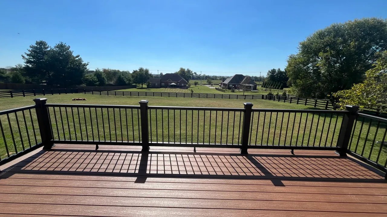 A spacious deck with a scenic view of a green field and houses.