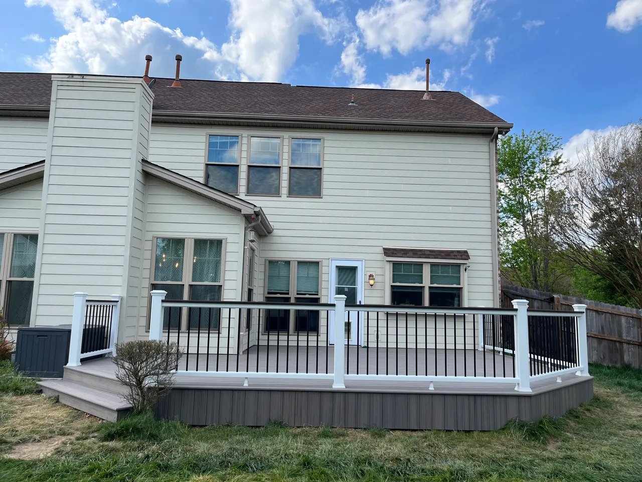 A modern home exterior featuring a new deck and railing.