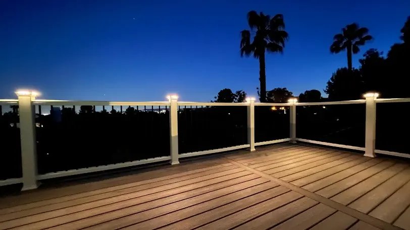 A beautifully illuminated deck at dusk surrounded by palm trees.