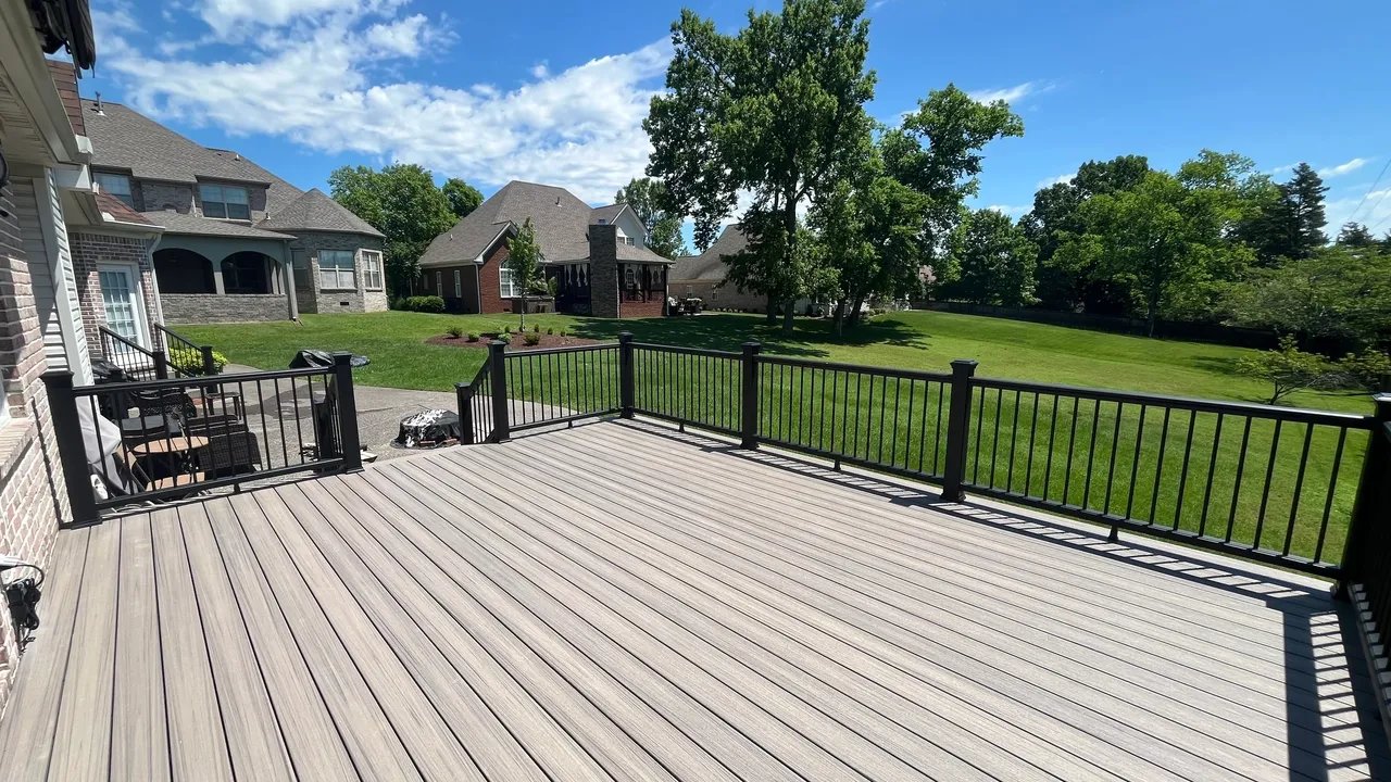 A spacious wooden deck overlooking a green lawn and houses.