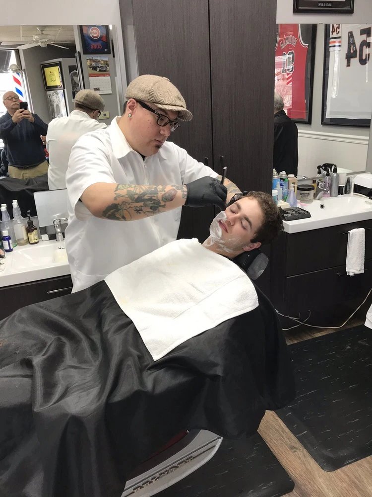 Barber giving a shave to a client in a modern barbershop